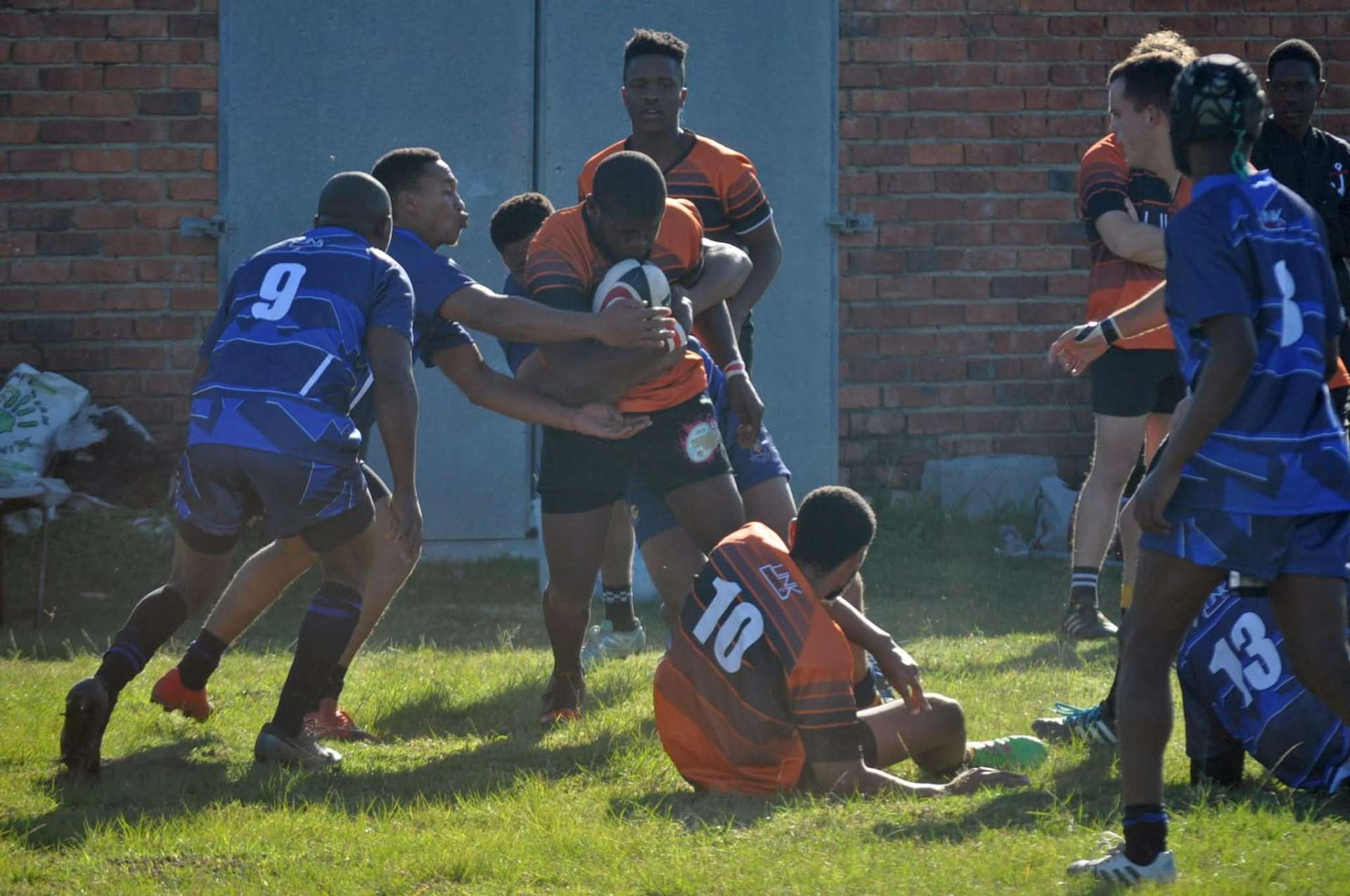 Olutsha Academy player carrying into contact against a blue-jerseyed side